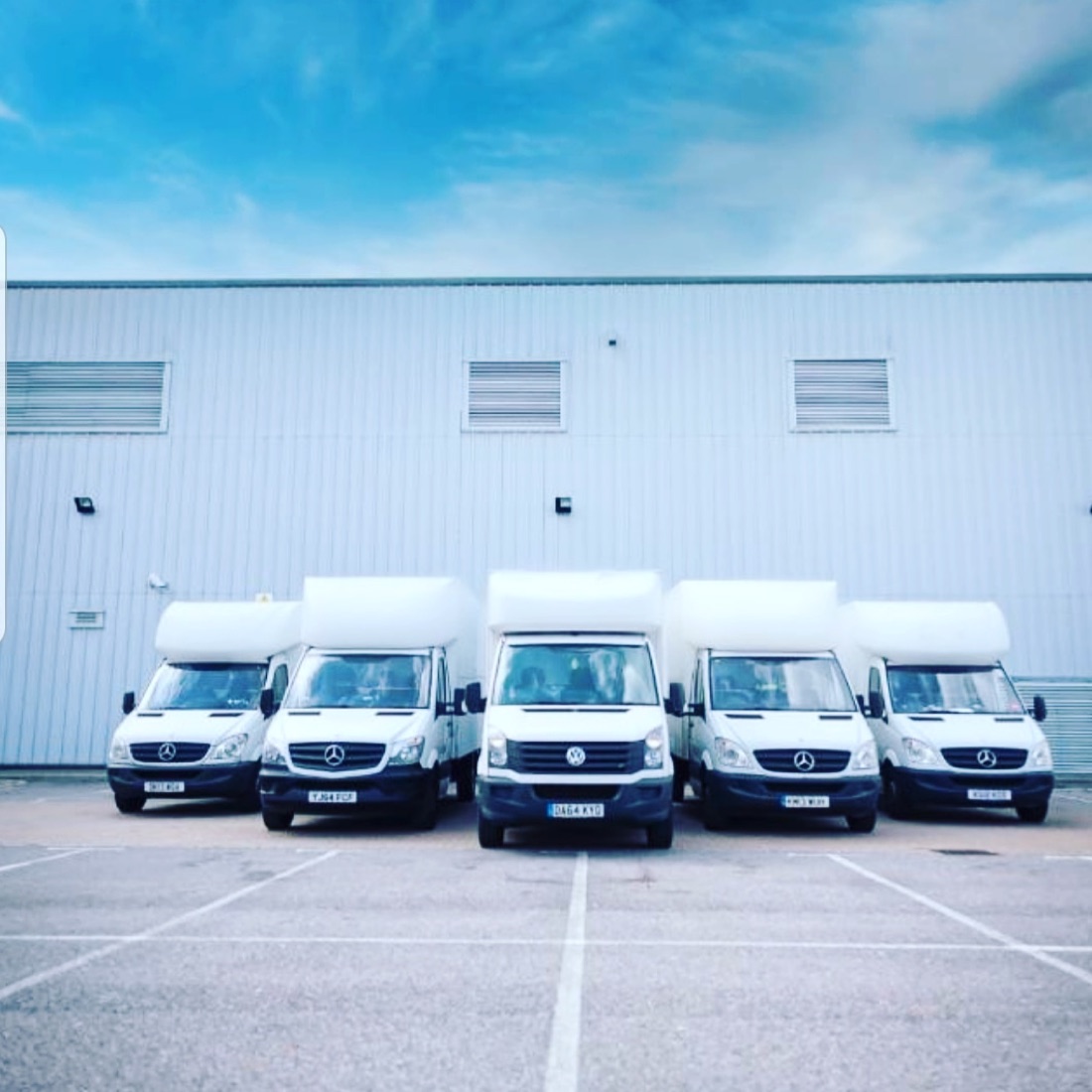 The Local Express Removals fleet of white Luton box vans lined up at their depot under a blue sky