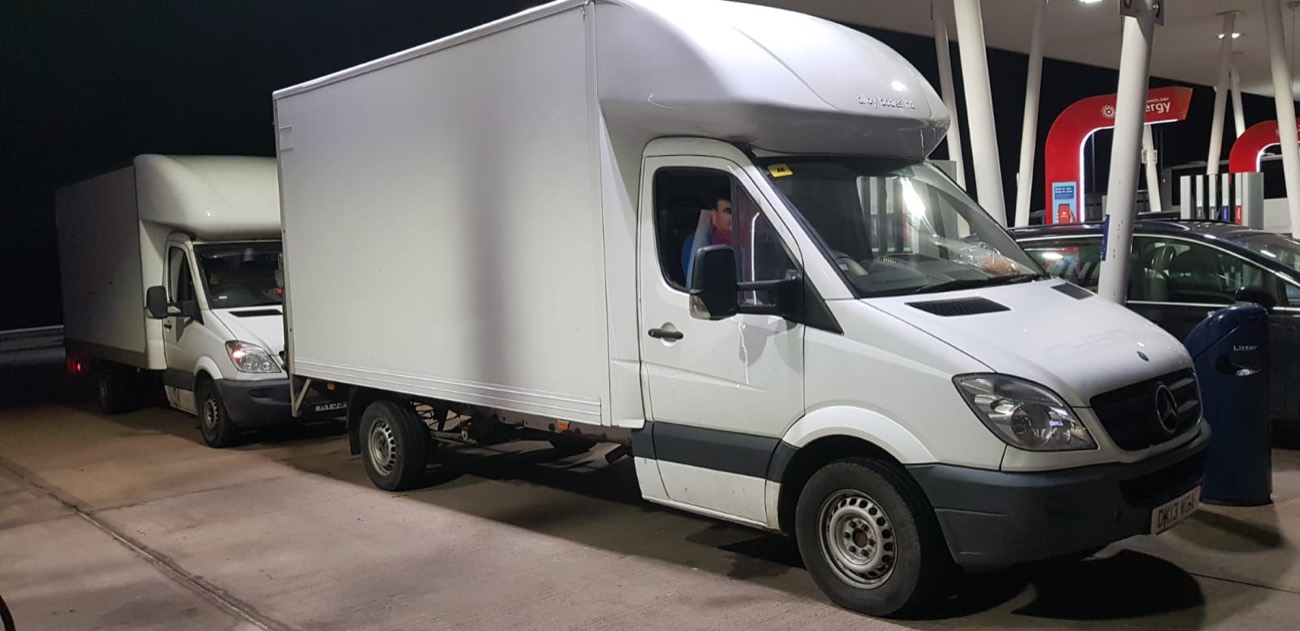 Two Local Express Removals Luton vans stopped at a service station at night on a long-distance move